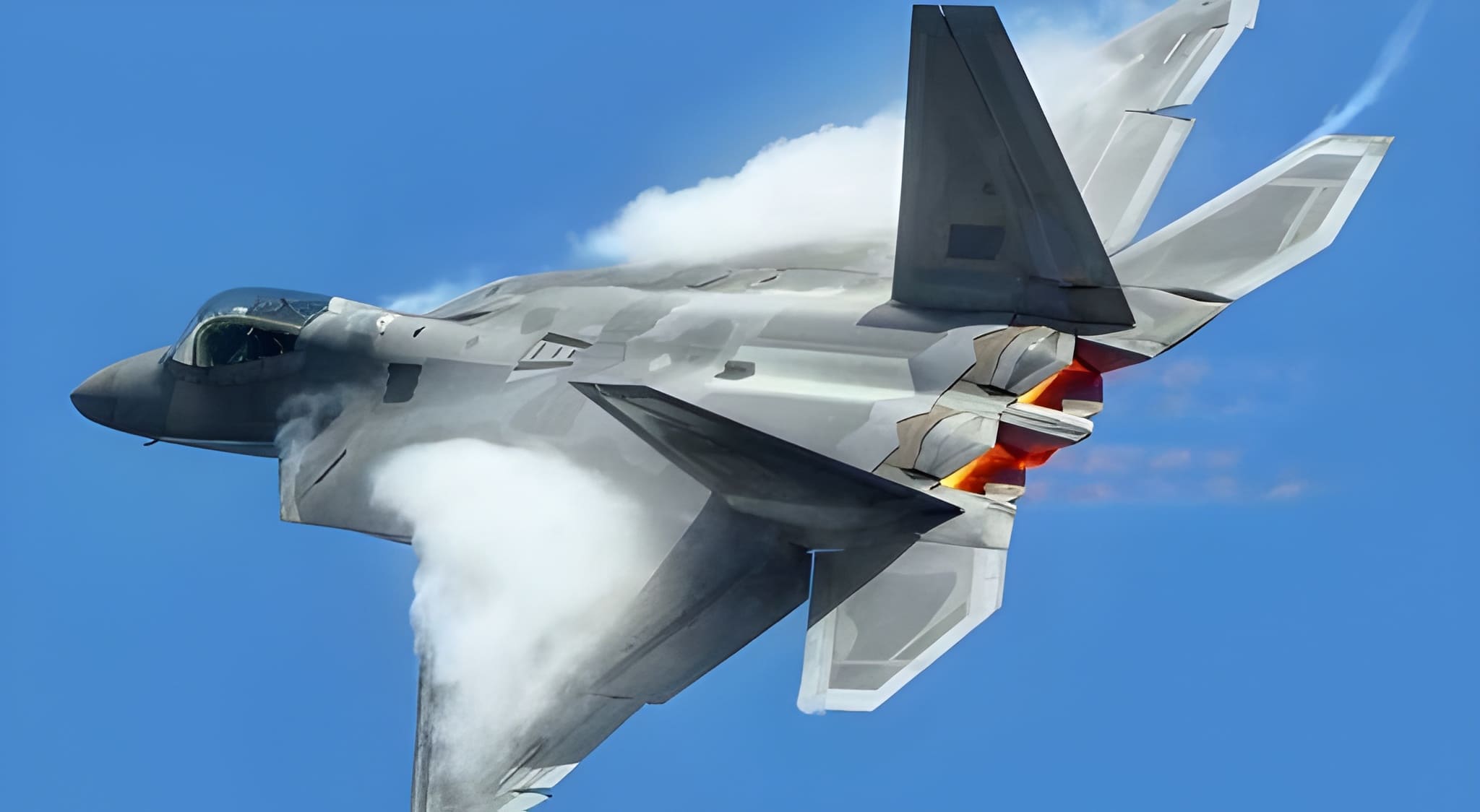 F-22 Raptor stealth fighter jet banking with afterburners glowing orange and vapor clouds forming over the wings