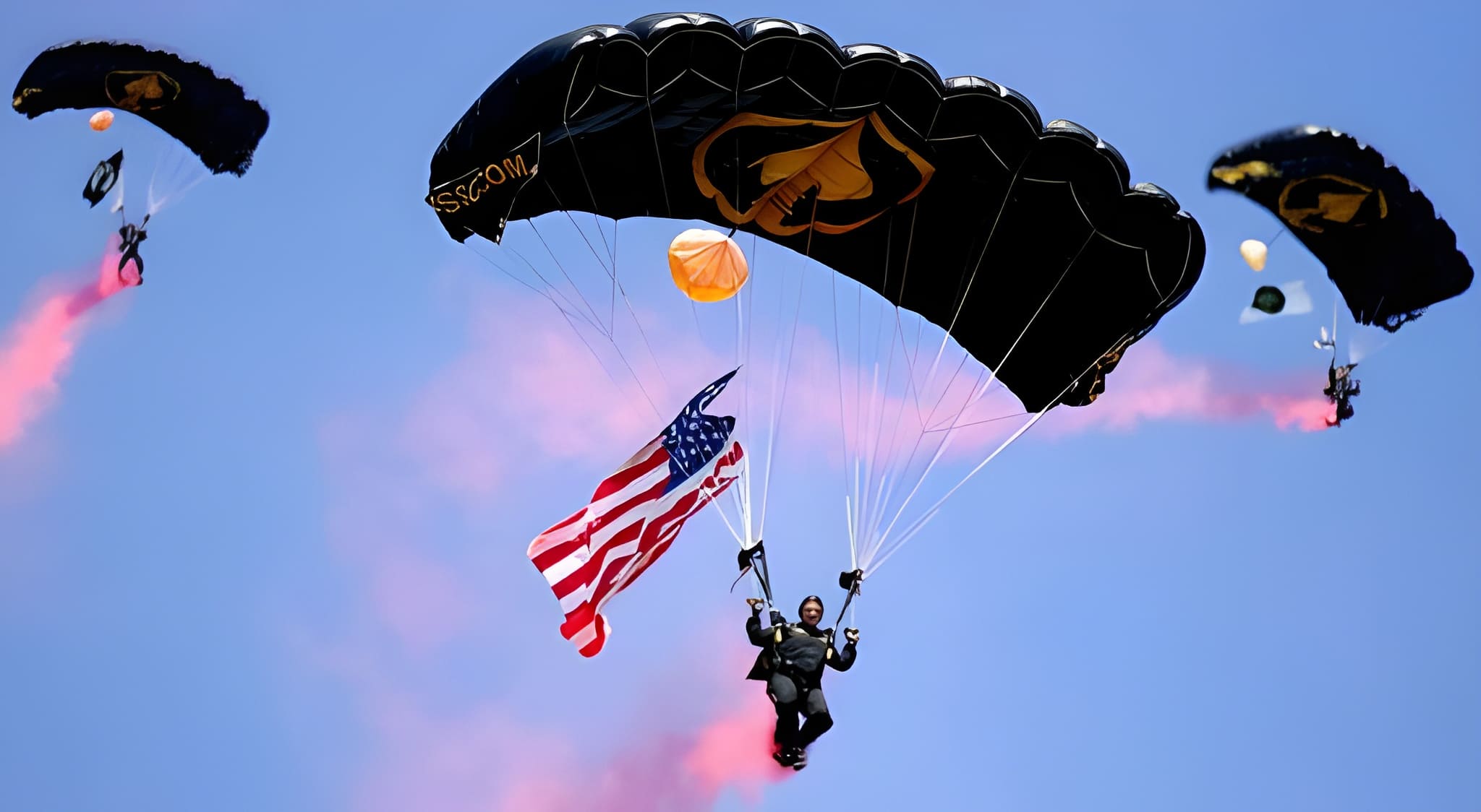SOCOM Para-Commandos parachuting with black U.S. Army canopies, American flag, and pink smoke trails against a blue sky