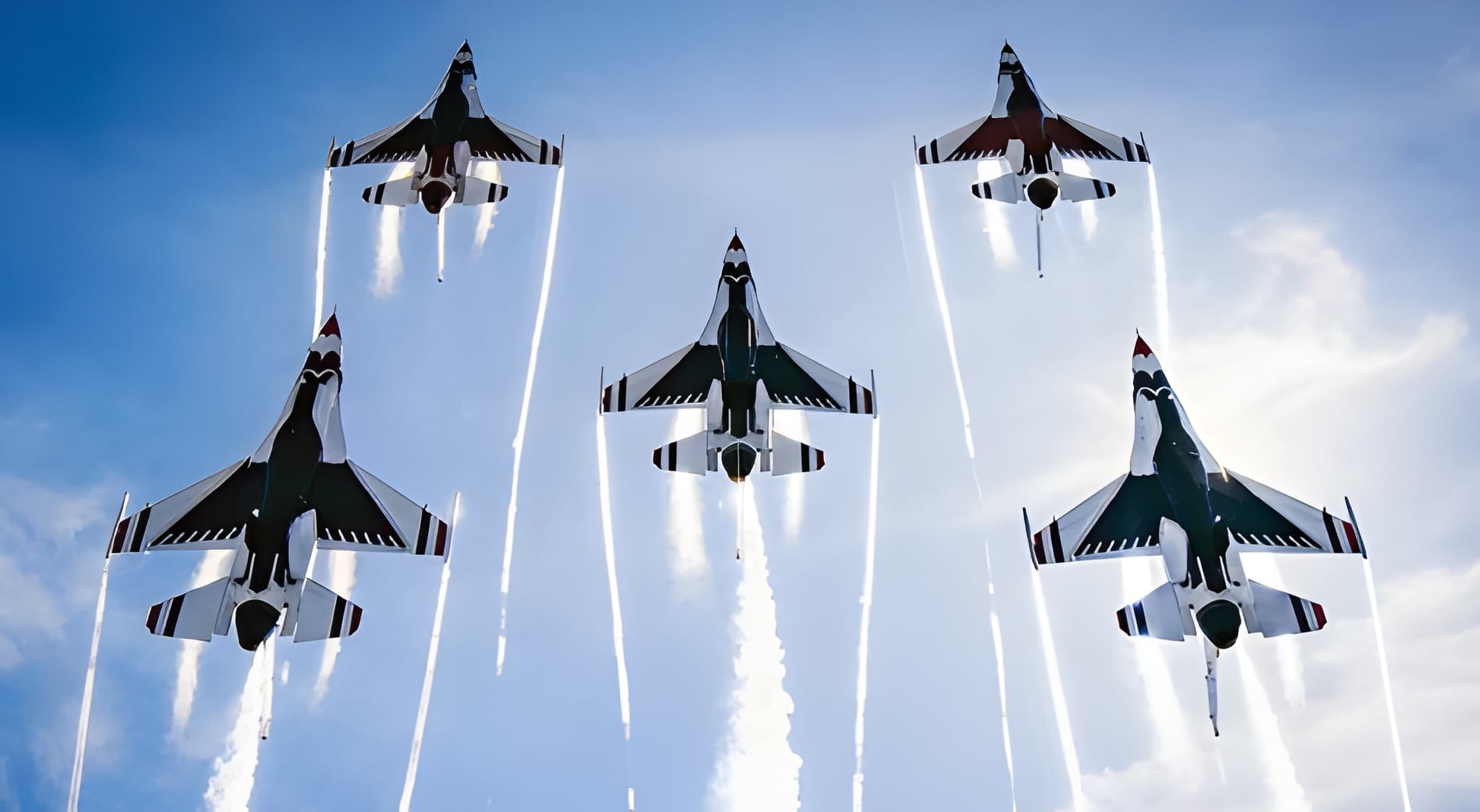 Five U.S. Air Force Thunderbirds in delta formation trailing white smoke streaks against a blue sky at the Fort Lauderdale Air Show