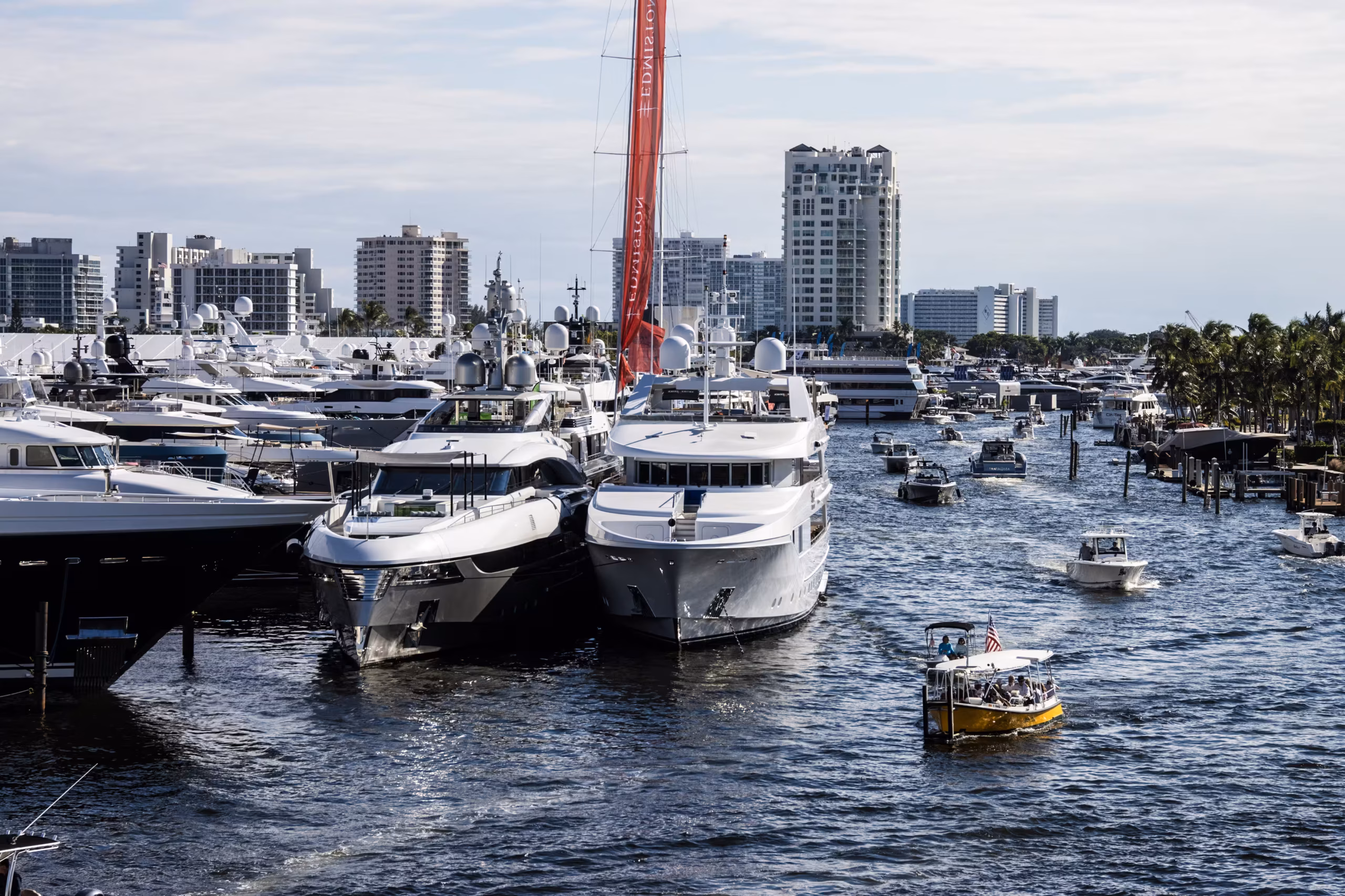 Yellow water taxi carrying passengers past superyachts docked along the Intracoastal during the Fort Lauderdale International Boat Show